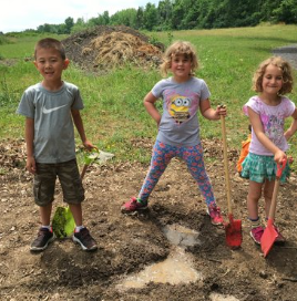 Photo of three kids digging in dirt outdoors